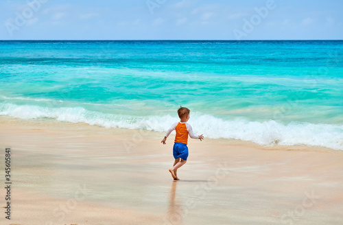 Three year old toddler boy running on beach