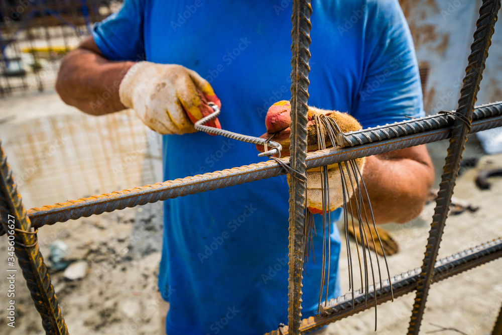 the worker staples the rebar with wire for durability, hands large the worker staples the rebar with wire for durability, hands large