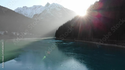 Drone flying above beautiful blue lake with mountains in the background 