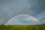 beautiful double rainbow on clouds  rainy day in rice field. after rain concept fresh air