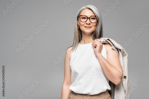smiling asian businesswoman in eyeglasses isolated on grey