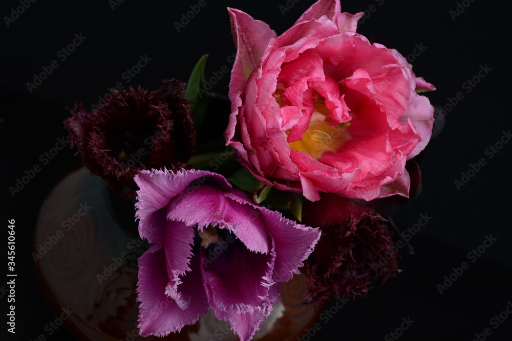 Beautiful composition of tulips in a clay vase on a dark background