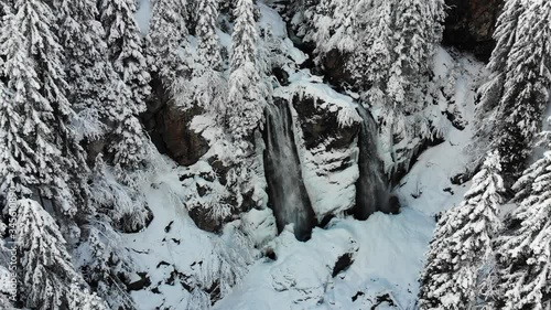 Drone shot of a waterfall in a snowy landscape 