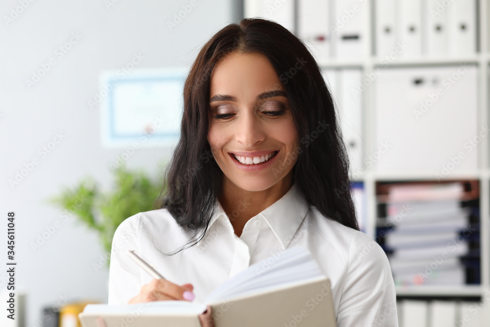 Beautiful woman smiles and makes diary entries. Fashion shopper deal with shape, texture fabric, geometry that this or that silhouette creates. Personal style, birth new look at oneself from inside