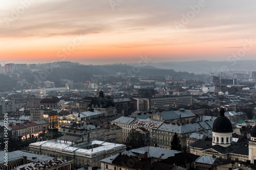 Beautiful, orange, fiery sunset over Lviv city in Ukraine. Cityscape with skyline and clouds. Town, buildings, towers, church and amazing sky.