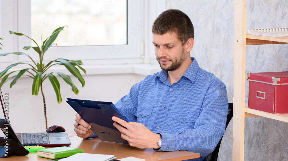 Office worker at the table reads documents in a folder Office worker at the table reads documents in a folder