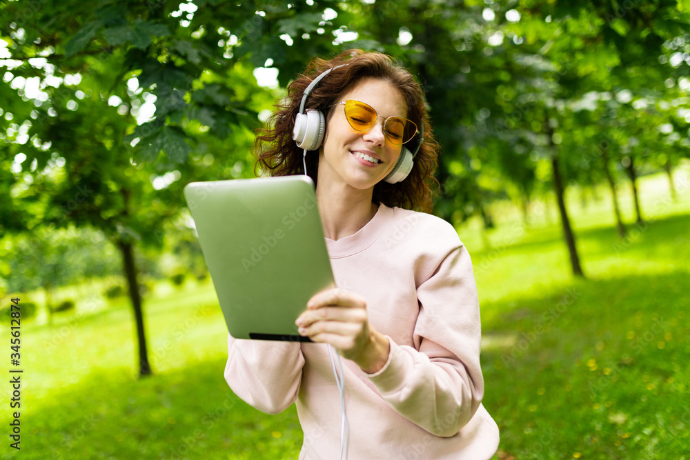 Pretty young caucasian woman go for a walk at park with tablet Pretty young caucasian woman go for a walk at park with tablet