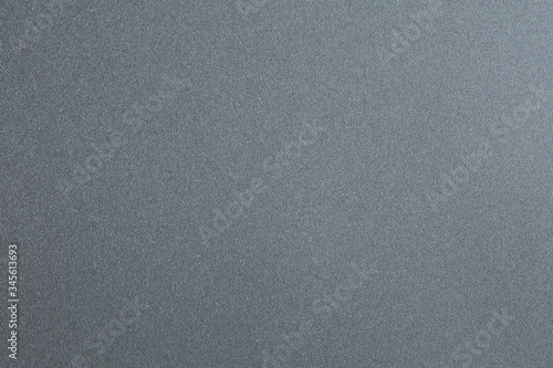The texture is grainy. Macro photo of a smooth gray plastic surface