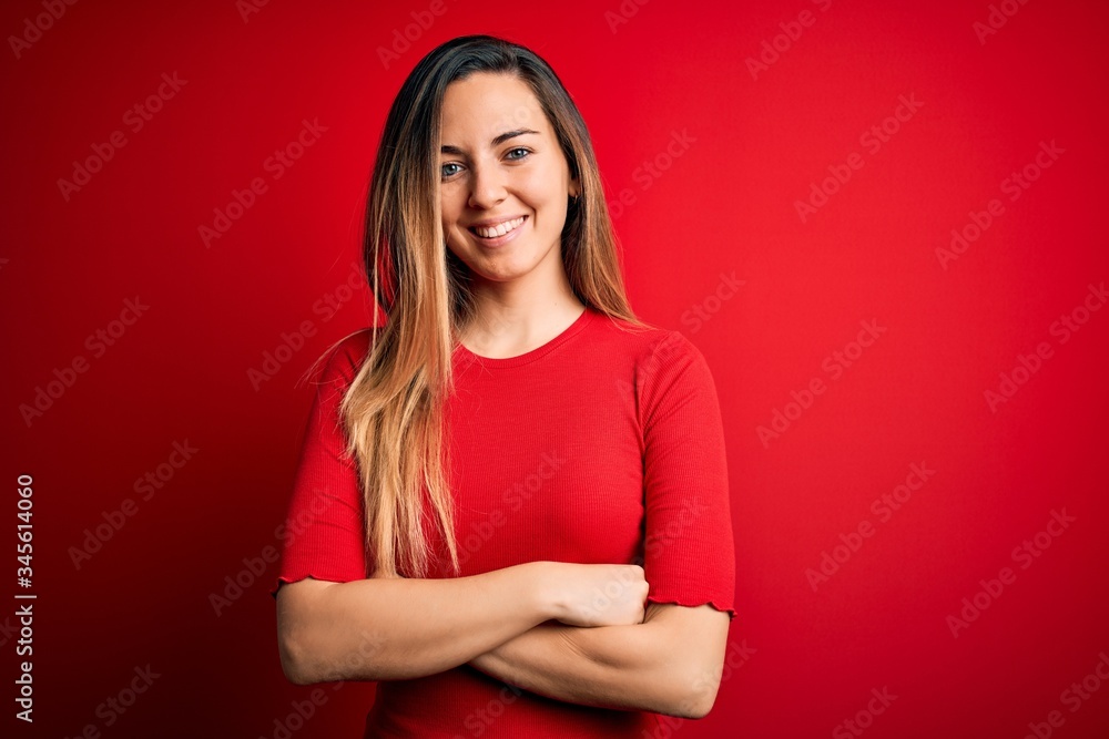 Young beautiful blonde woman with blue eyes wearing casual t-shirt over red background happy face smiling with crossed arms looking at the camera. Positive person. Young beautiful blonde woman with blue eyes wearing casual t-shirt over red background happy face smiling with crossed arms looking at the camera. Positive person.
