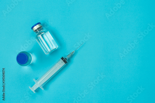 Table top view accessories healthcare & medical with coronavirus background concept.Anti retroviral vaccine bottle with Syringe on blue paper.Flat lay items for doctor using treat patient Covid-19.