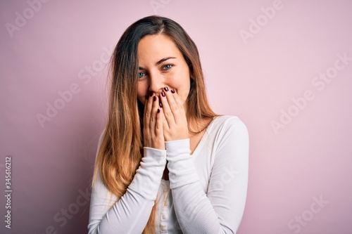 фотографія Young beautiful blonde woman with blue eyes wearing white t-shirt over pink back