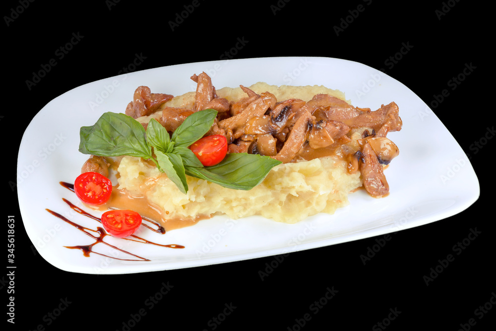 Tasty meat in small pieces on mashed potatoes with cherry tomatoes, on a white plate, isolated on black background Tasty meat in small pieces on mashed potatoes with cherry tomatoes, on a white plate, isolated on black background