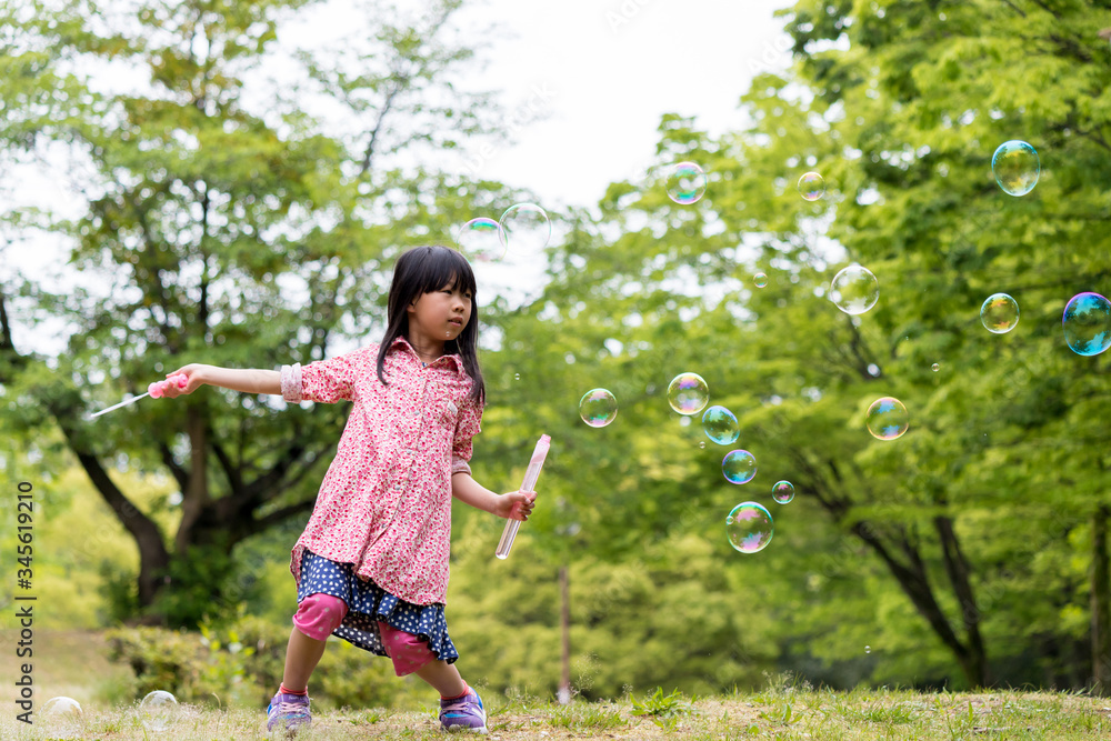 春の公園でシャボン玉を遊んでいる可愛い子供