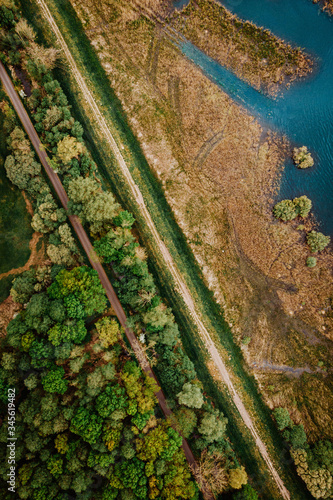 road through wood with blue water