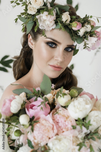 The bride holds a wedding bouquet, wedding dress, wedding details. wedding bouquet of peonies. Bride with snatural wreath of fresh flowers. Hairstyle from volumetric braids. lifestyle, fashion photo