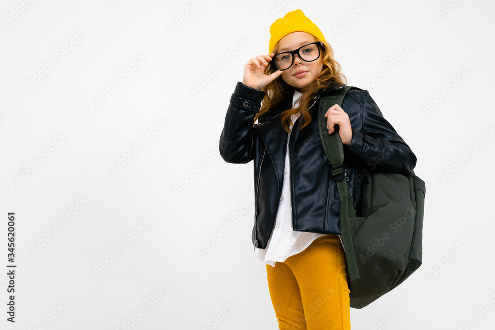 European attractive girl dressed in a yellow hat, glasses and a leather jacket with a backpack on her back on a white background with copyspace European attractive girl dressed in a yellow hat, glasses and a leather jacket with a backpack on her back on a white background with copyspace