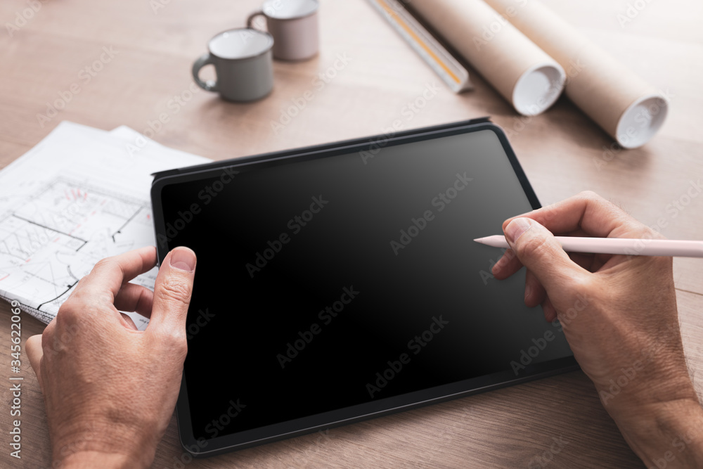 Tablette tenue en main avec un stylet par un architecte travaillant sur un projet de construction d'une maison ou d'un projet industriel