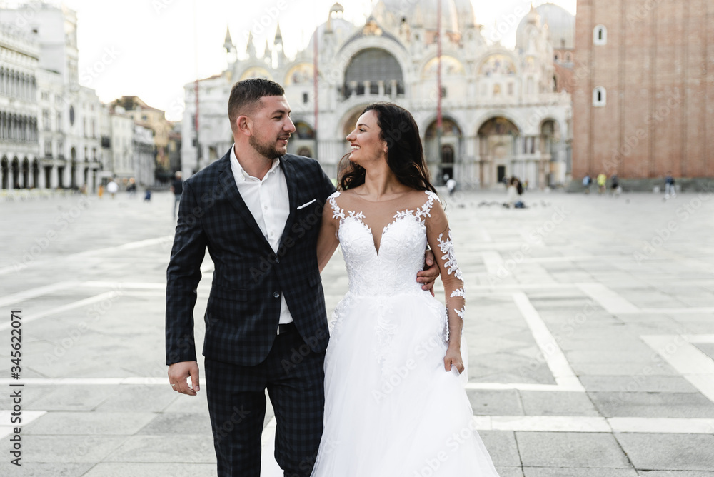 Naklejka premium happy bride and groom cuddle during a wedding walk,lovely couple's wedding day,beautiful outfits of the newlyweds,