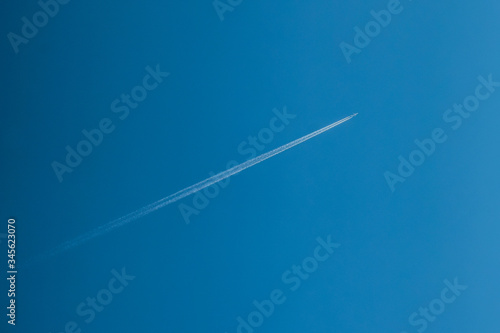 View of plane contrail on the sky. White line on blue background.
