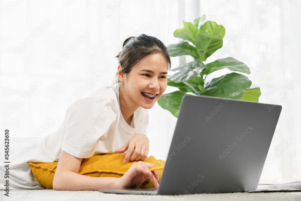 Happy young Asian woman working for laptop from home on the carpet. Happy young Asian woman working for laptop from home on the carpet.