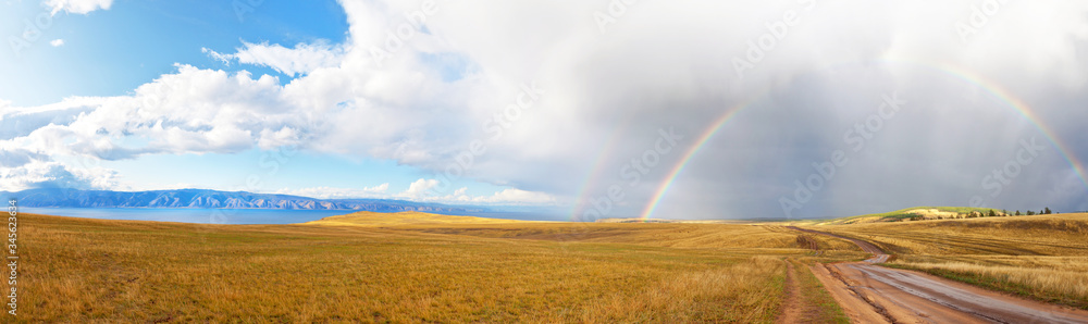 Baikal Lake. Beautiful panoramic view of the steppe part of Olkhon Island with a rainbow over a dirt road at Cape Khoboy. Autumn landscape, natural background