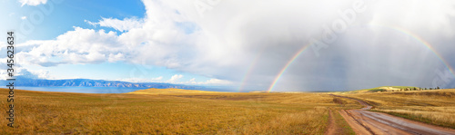 Baikal Lake. Beautiful panoramic view of the steppe part of Olkhon Island with a rainbow over a dirt road at Cape Khoboy. Autumn landscape, natural background
