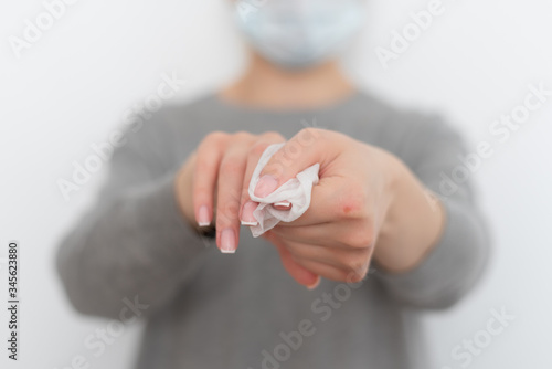 woman in a gray hoodie wipes her hands with a napkin on a white background