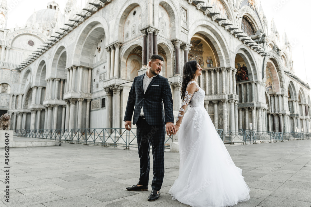 Obraz premium bride and groom on the background of a historic building,bride and groom walk the streets of the old city of venice,newlyweds dance,european wedding,quarantine wedding