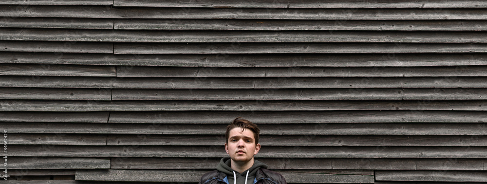 young man looking into camera seriously on wooden background
young man looking into camera seriously on wooden background