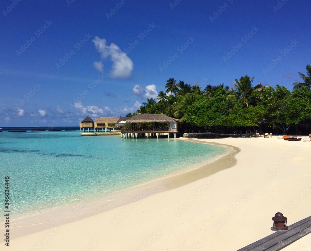 A picture of a Maldivian shore at Constance Moofushi Maldives with clear blue Laccadive sea, beautiful bungalows and blue sky in the background