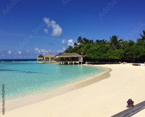 Fototapeta Naklejka Na Ścianę i Meble -  A picture of a Maldivian shore at Constance Moofushi Maldives with clear blue Laccadive sea, beautiful bungalows and blue sky in the background