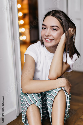 Pensive girl with big dark eyes sitting on the floor. Smiling beautiful lady in pajamas spending weekend in her apartment. Free Download Pensive girl with big dark eyes sitting on the floor. Smiling beautiful lady in pajamas spending weekend in her apartment. - GFXLoad