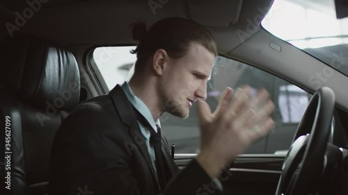 Right sight view of angry man is shouting sitting in the car on a driver's seat and using his phone. Businessman yelling while driving a car.