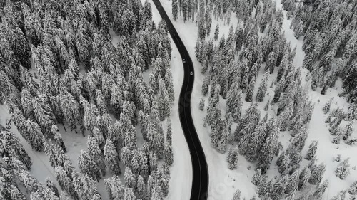 Aerial footage of car driving along curvy road in snow covered landscape