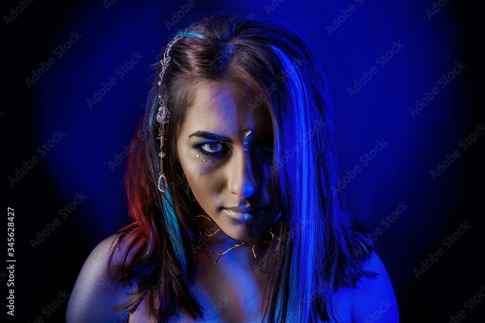 Naklejka premium ethnic girl on a black background in blue light