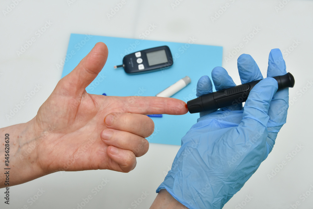 Fototapeta premium Close up of woman hands using black lancet on finger to check blood sugar level 