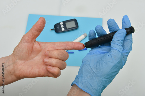 Close up of woman hands using black  lancet on finger to check blood sugar level 