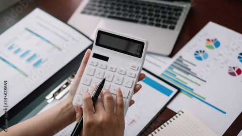 Close up Businessman using calculator and laptop for calaulating finance, tax, accounting, statistics and analytic research concept