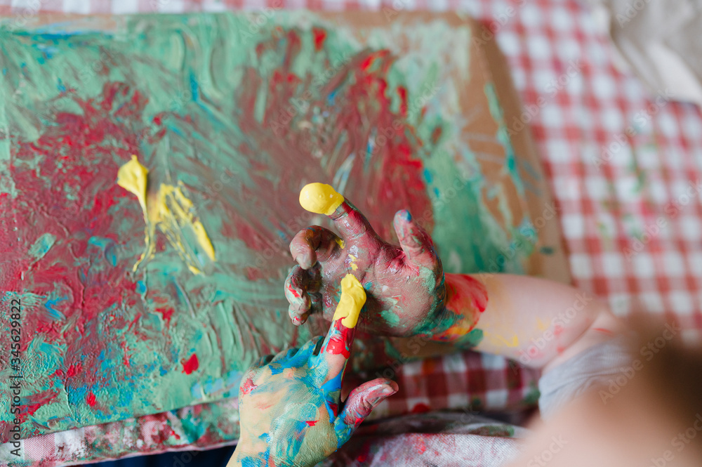 kleines Kind malt mit bunter Fingerfarbe 