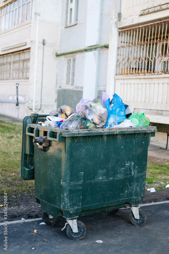 full trash can on the background of a prefabricated house full trash can on the background of a prefabricated house