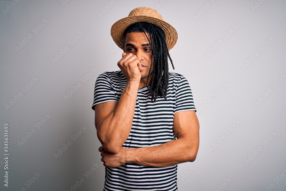 Young african american man with dreadlocks on vacation wearing striped t-shirt and hat looking stressed and nervous with hands on mouth biting nails. Anxiety problem. Young african american man with dreadlocks on vacation wearing striped t-shirt and hat looking stressed and nervous with hands on mouth biting nails. Anxiety problem.