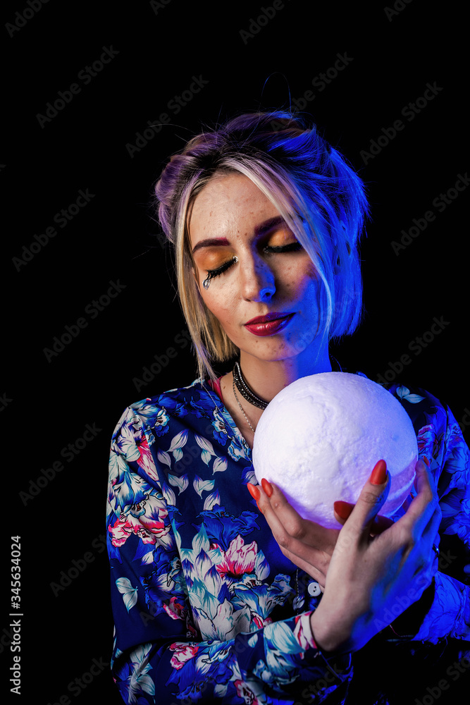 Naklejka premium Infantile girl on a black background in blue light