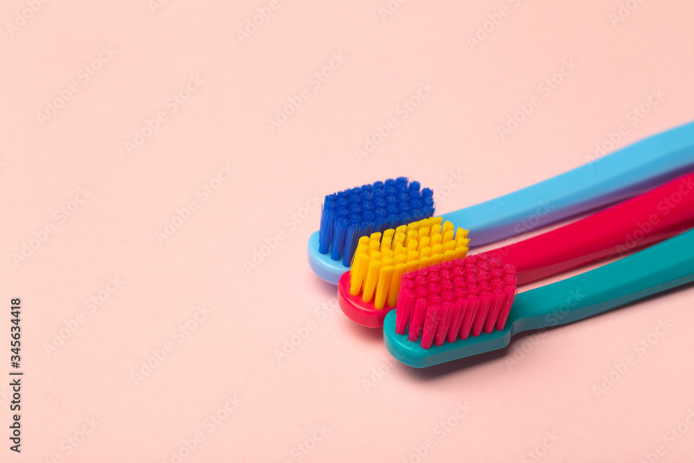 Toothbrushes of different colors on a pink background. Brushing teeth and oral hygiene. Toothbrushes of different colors on a pink background. Brushing teeth and oral hygiene.