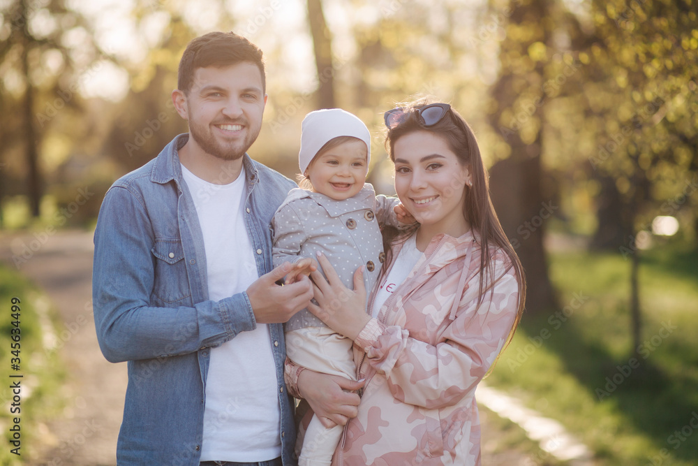 Portrait of happy family in the park. Father mother and litthe daughter. Adorable little with with mom and dad. Young family, Handsome dad and attractive young mom. Happy Mother's Day Portrait of happy family in the park. Father mother and litthe daughter. Adorable little with with mom and dad. Young family, Handsome dad and attractive young mom. Happy Mother's Day