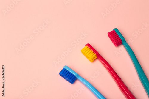 Toothbrushes of different colors on a pink background. Brushing teeth and oral hygiene.