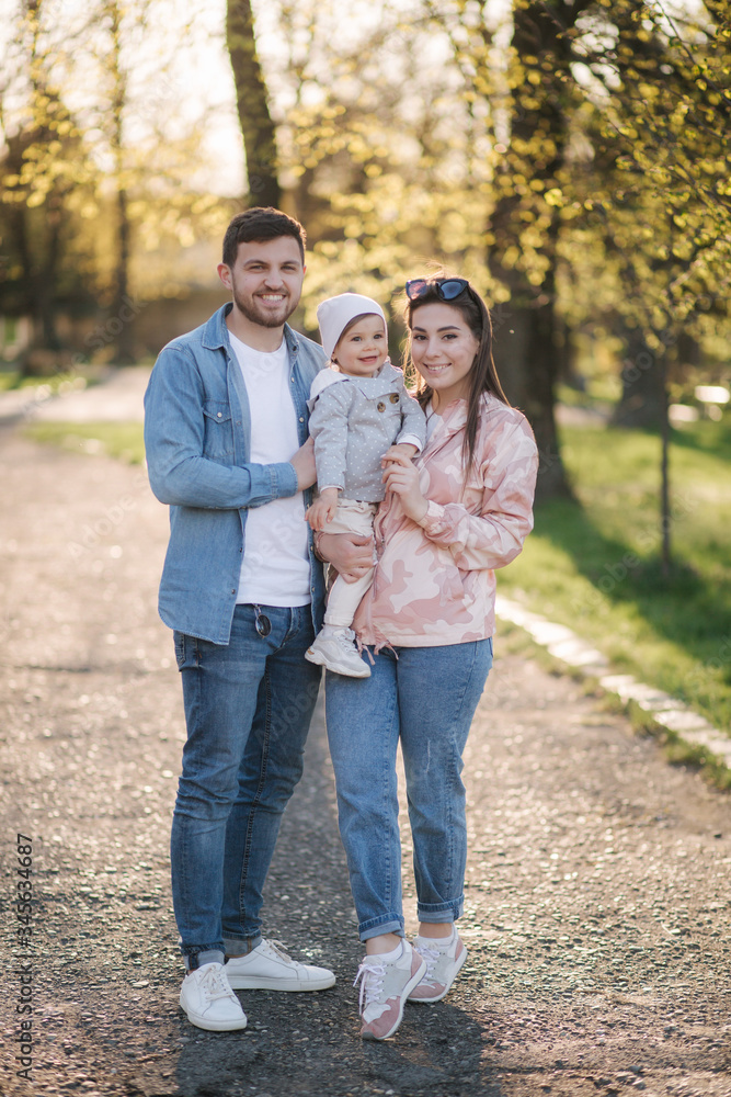 Portrait of happy family in the park. Father mother and litthe daughter. Adorable little with with mom and dad. Young family, Handsome dad and attractive young mom. Happy Mother's Day Portrait of happy family in the park. Father mother and litthe daughter. Adorable little with with mom and dad. Young family, Handsome dad and attractive young mom. Happy Mother's Day