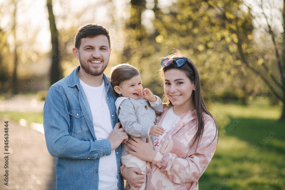 Portrait of happy family in the park. Father mother and litthe daughter. Adorable little with with mom and dad. Young family, Handsome dad and attractive young mom. Happy Mother's Day Portrait of happy family in the park. Father mother and litthe daughter. Adorable little with with mom and dad. Young family, Handsome dad and attractive young mom. Happy Mother's Day