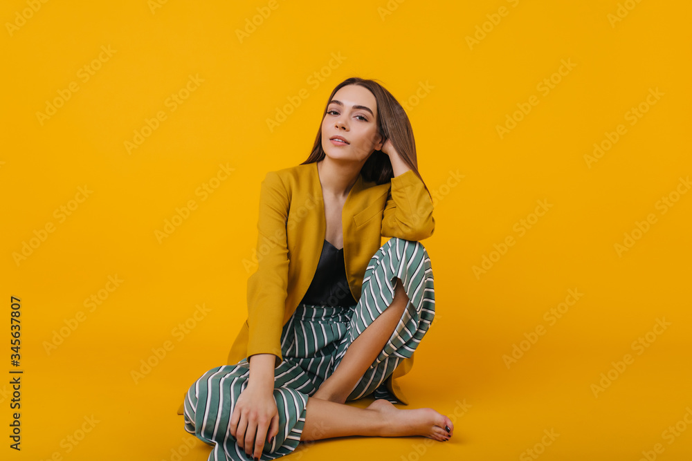 Wonderful female model wears striped pants posing in studio. Indoor photo of enthusiastic brunette girl isolated on bright background. Wonderful female model wears striped pants posing in studio. Indoor photo of enthusiastic brunette girl isolated on bright background.