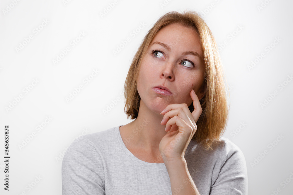The concept of psychology and emotions. Young woman blonde rested his cheek on his hand, and looks thoughtfully to the side. White background. Copy space The concept of psychology and emotions. Young woman blonde rested his cheek on his hand, and looks thoughtfully to the side. White background. Copy space