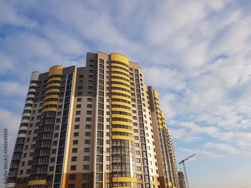 Fototapeta premium Close-up of luxury high apartment complex. Fragment of modern residential flat exterior. Blue sky with clouds. Real estate property and posh architecture concept